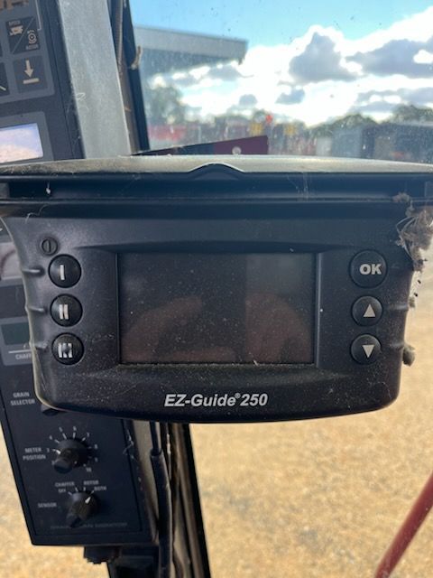 EZ-Guide 250 GPS display mounted in a vehicle cab, with buttons and blank screen visible.