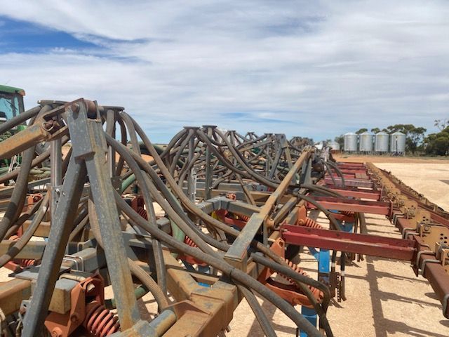 Rows of metal framework and red beams on a sandy beach under a cloudy sky