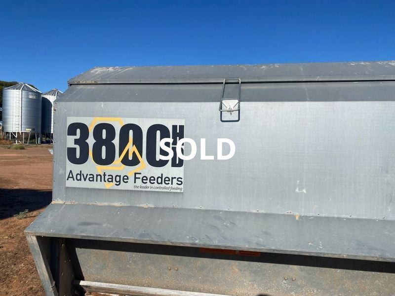 Gray livestock feeder marked “380H SOLD” with Advantage Feeders logo outdoors under a blue sky