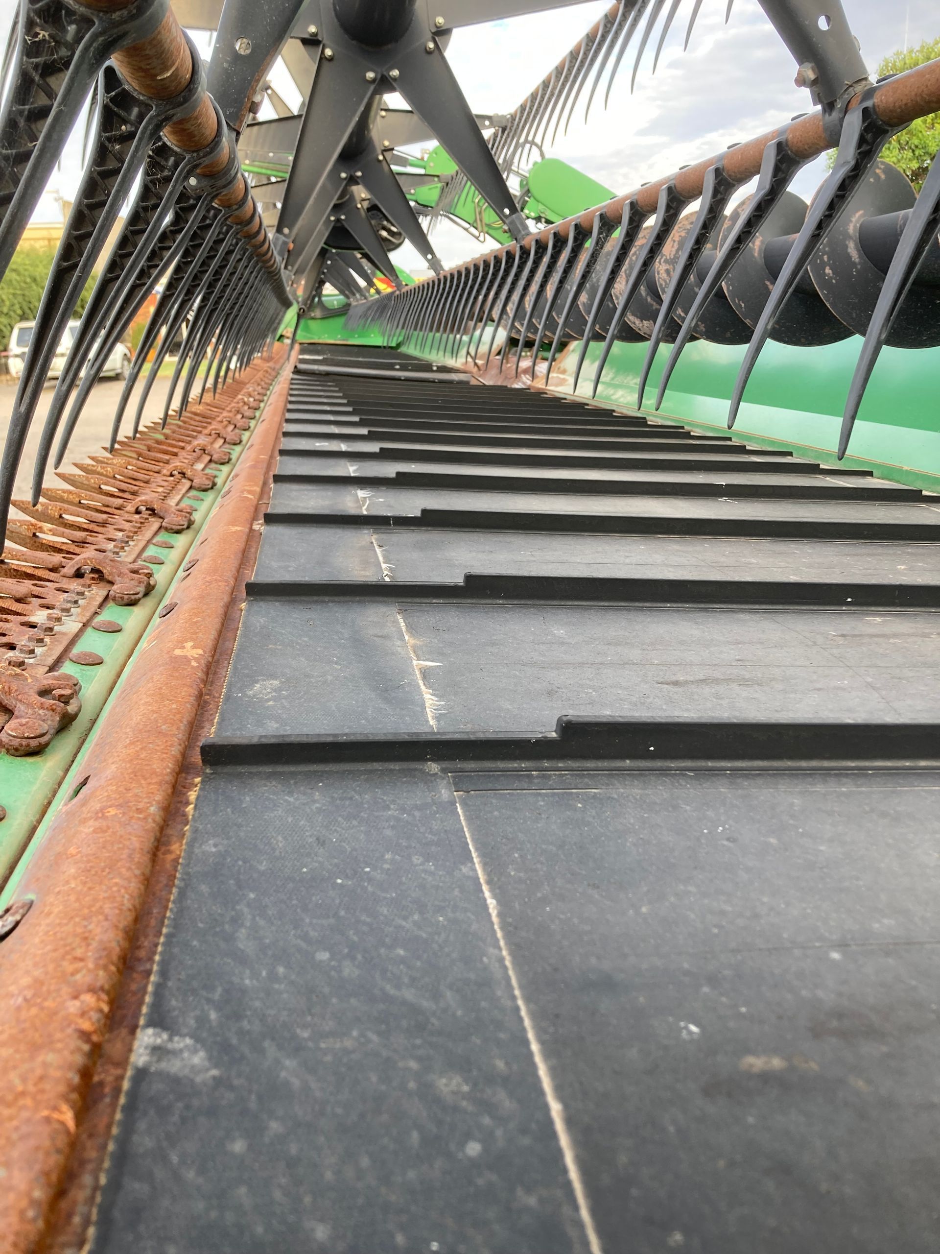 Inclined black conveyor belt with orange rails and metal framework in an industrial setting