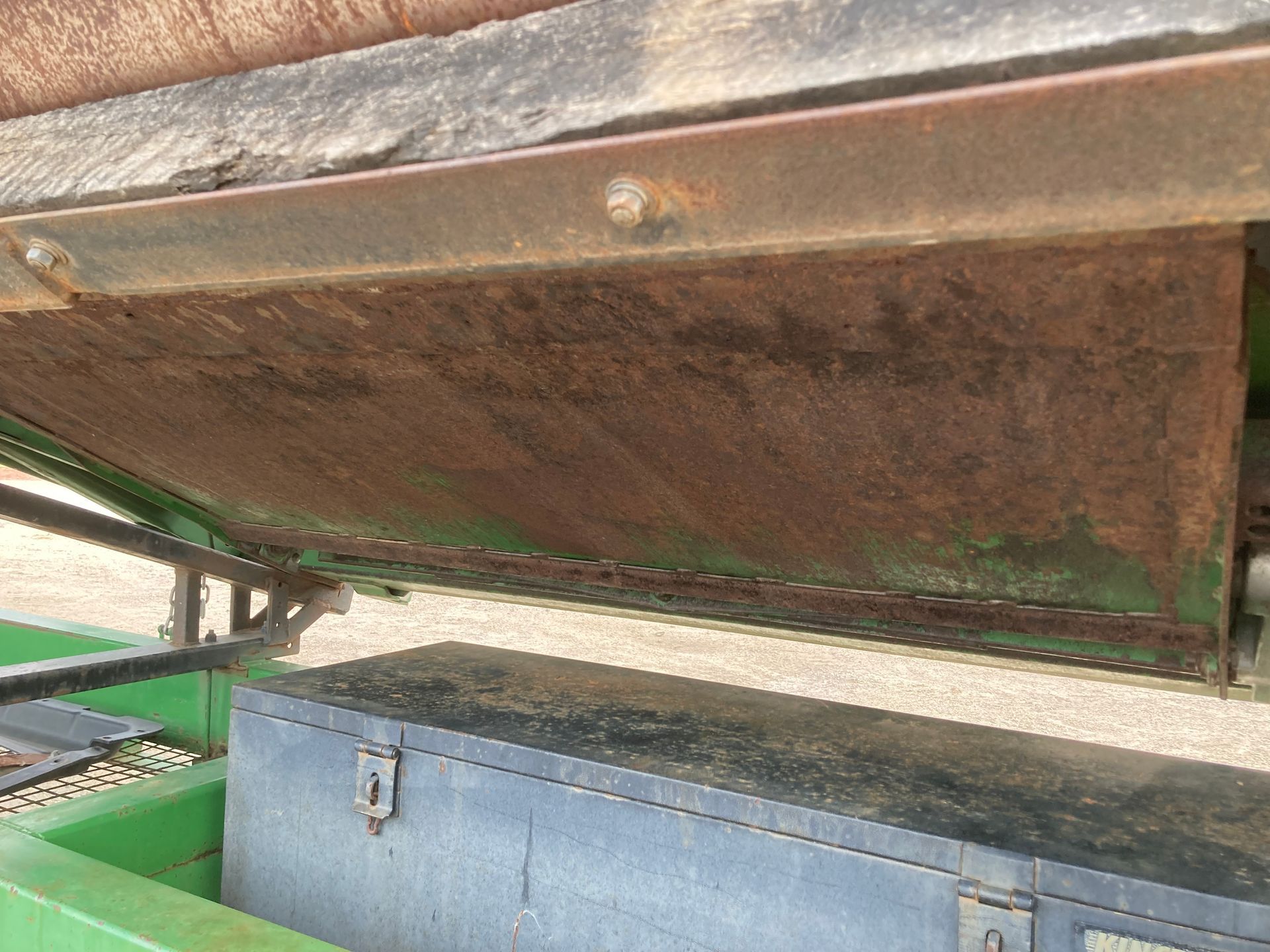 Rusty metal hopper above a blue storage bin on a green industrial frame