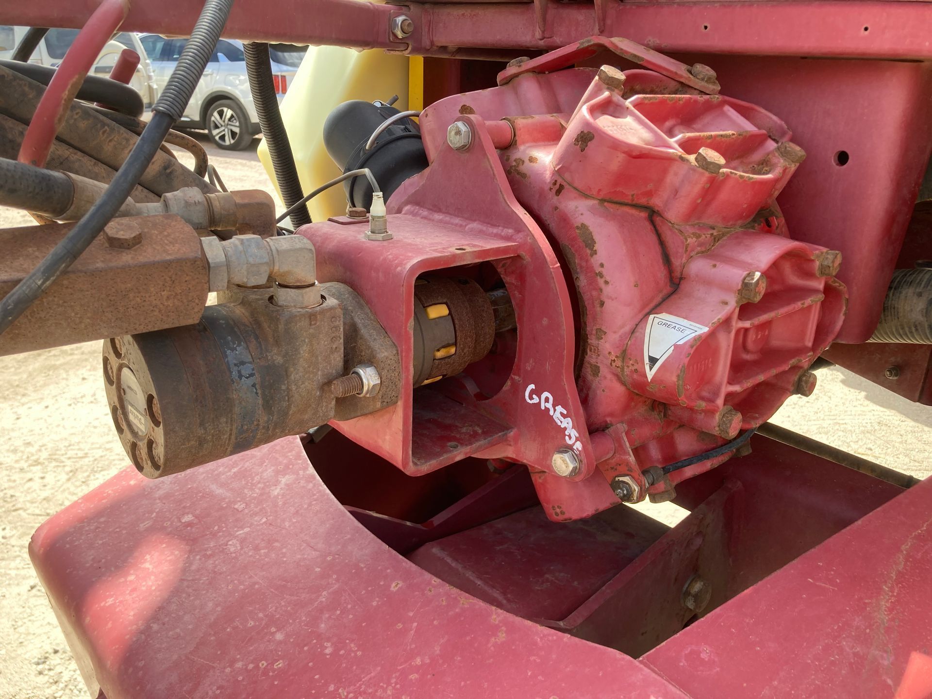 Close-up of a red hydraulic motor and hoses mounted on farm machinery.