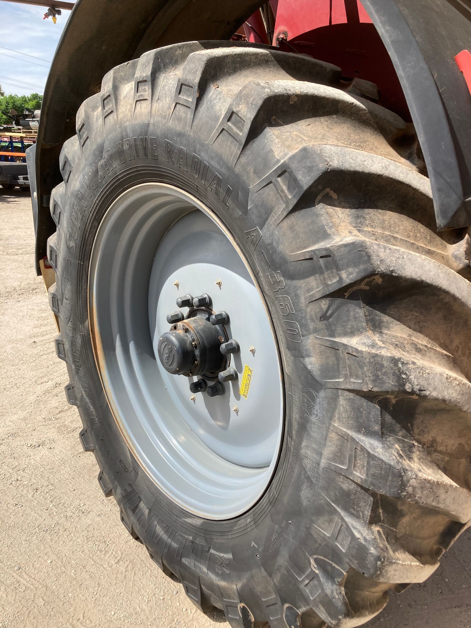 Close-up of a large tractor tire with deep treads and a white rim on farm machinery