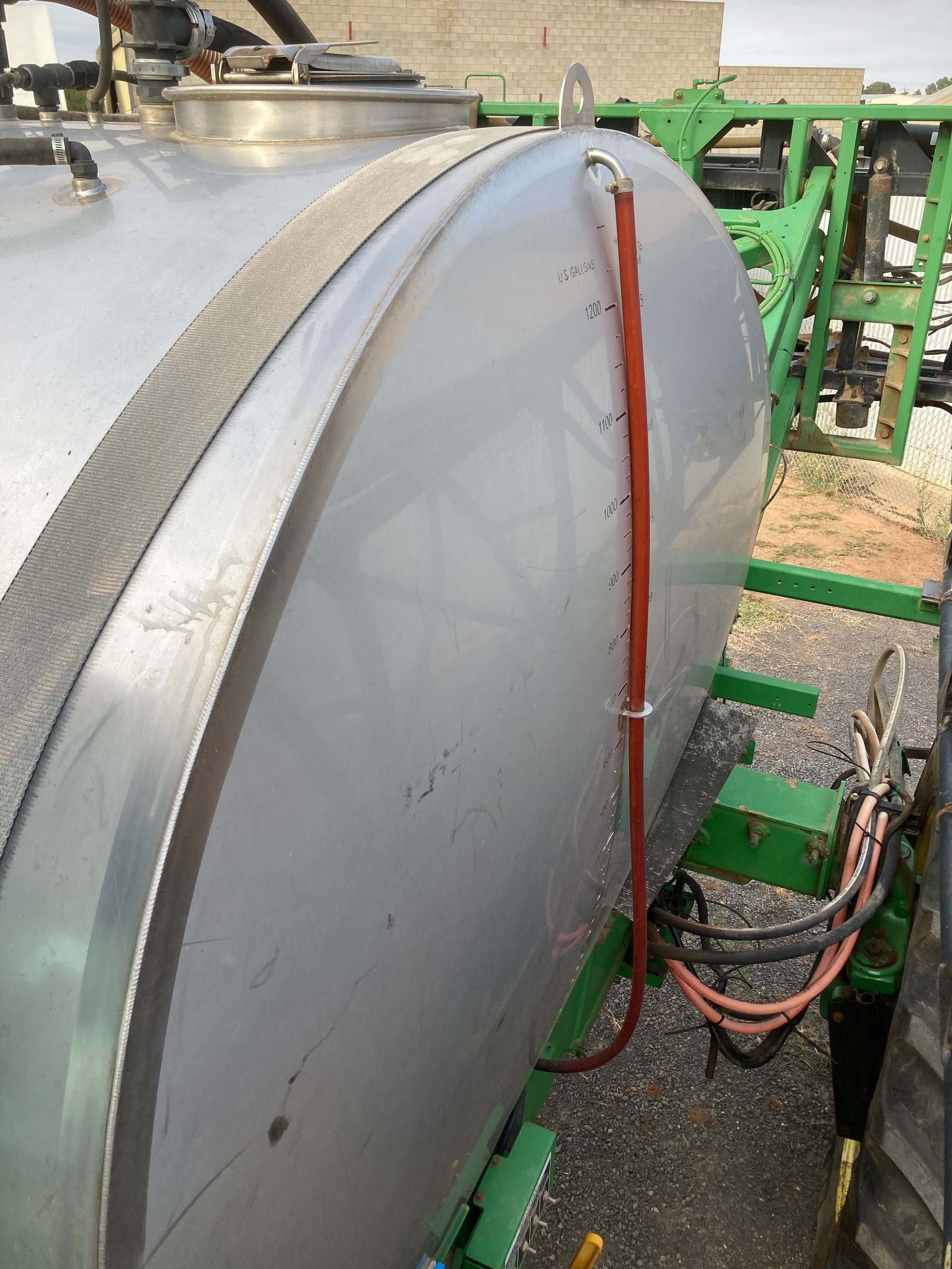 Large white industrial tank with a red hose and green metal framework outdoors