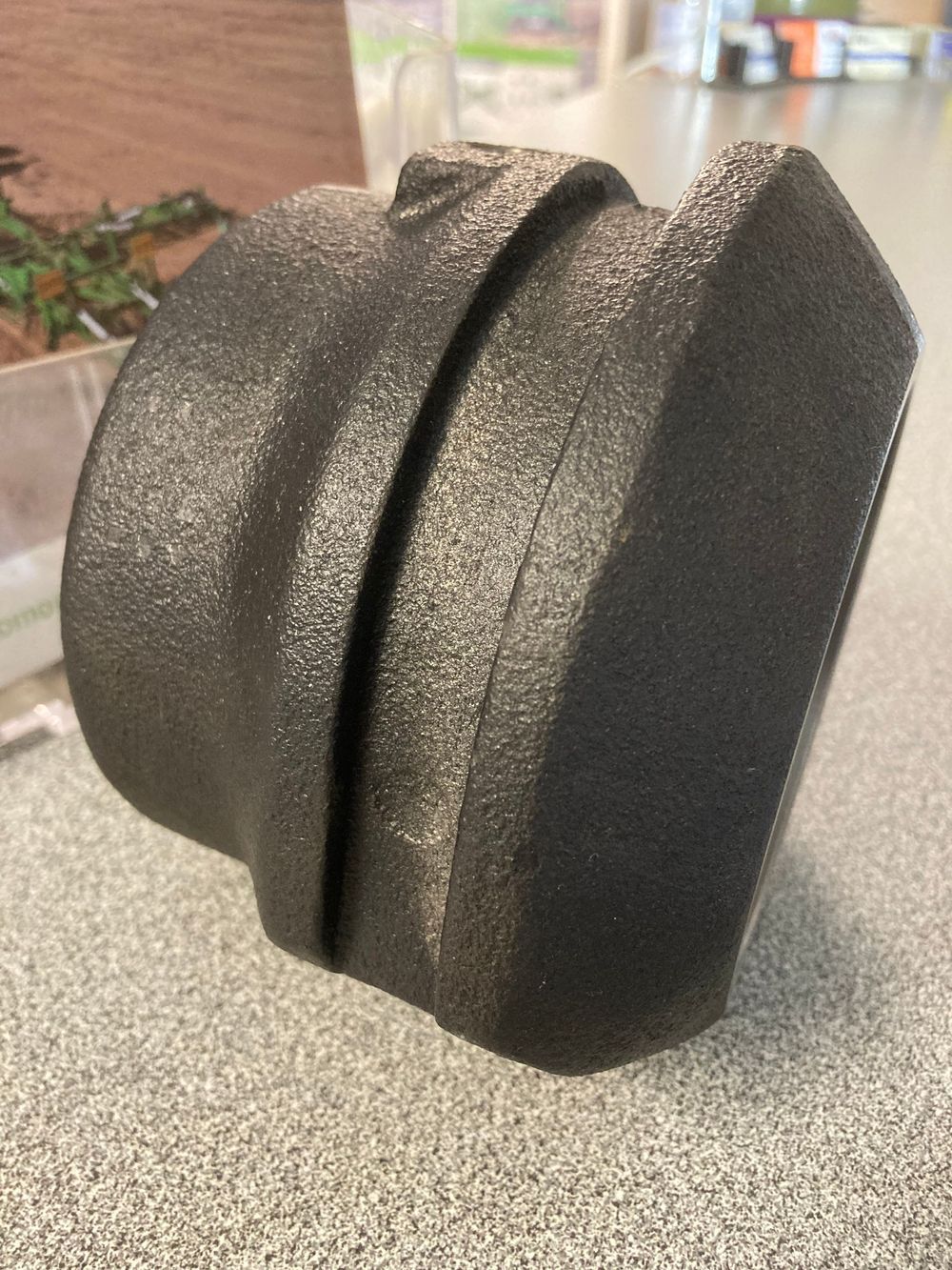 Black textured plastic knob or cap on a countertop, shown in close-up from the side