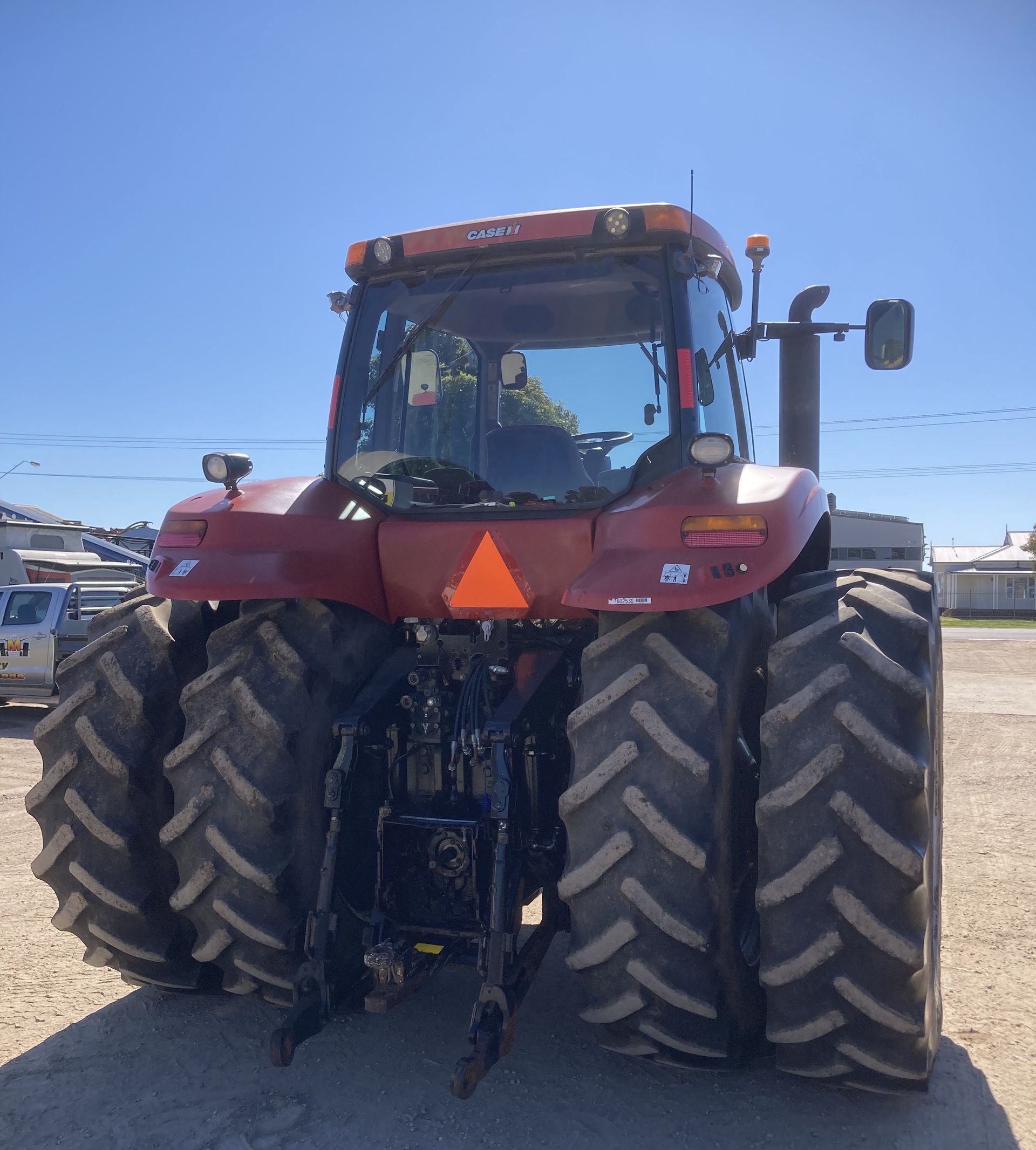 Front view of a red tractor with dual large tires parked outdoors under a clear sky