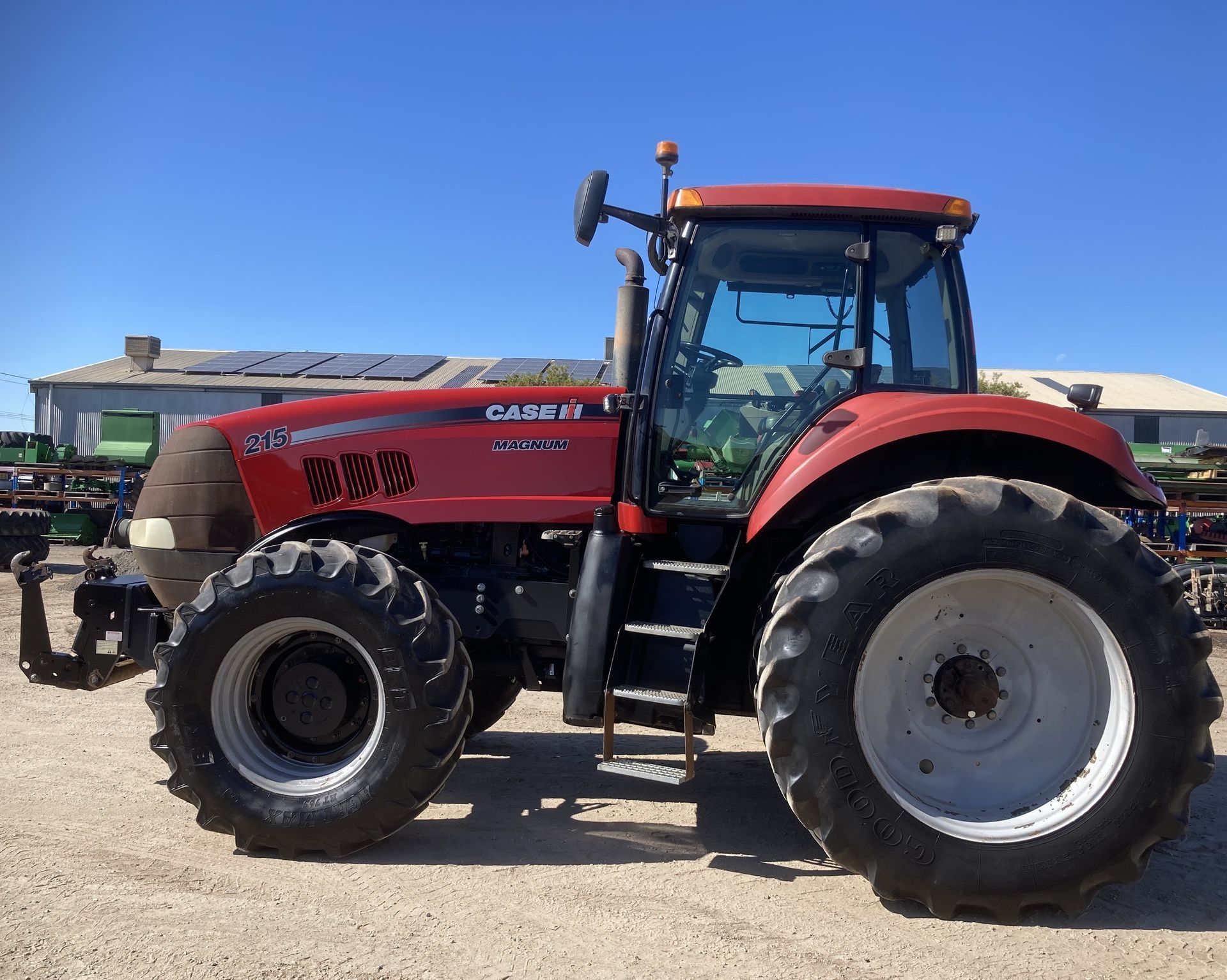 Red tractor parked on a gravel lot under a blue sky