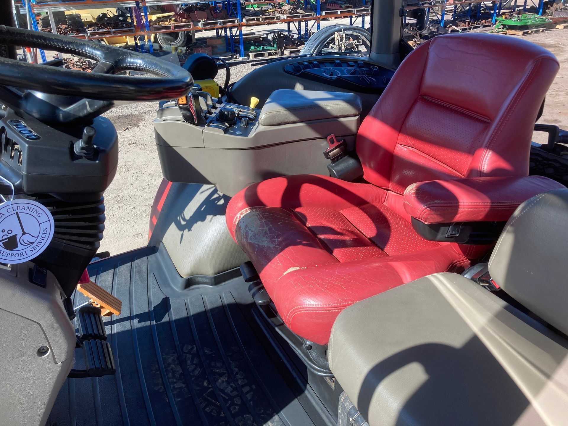 Red cushioned boat seating on a deck at a marina, with a steering wheel and other boats in the background