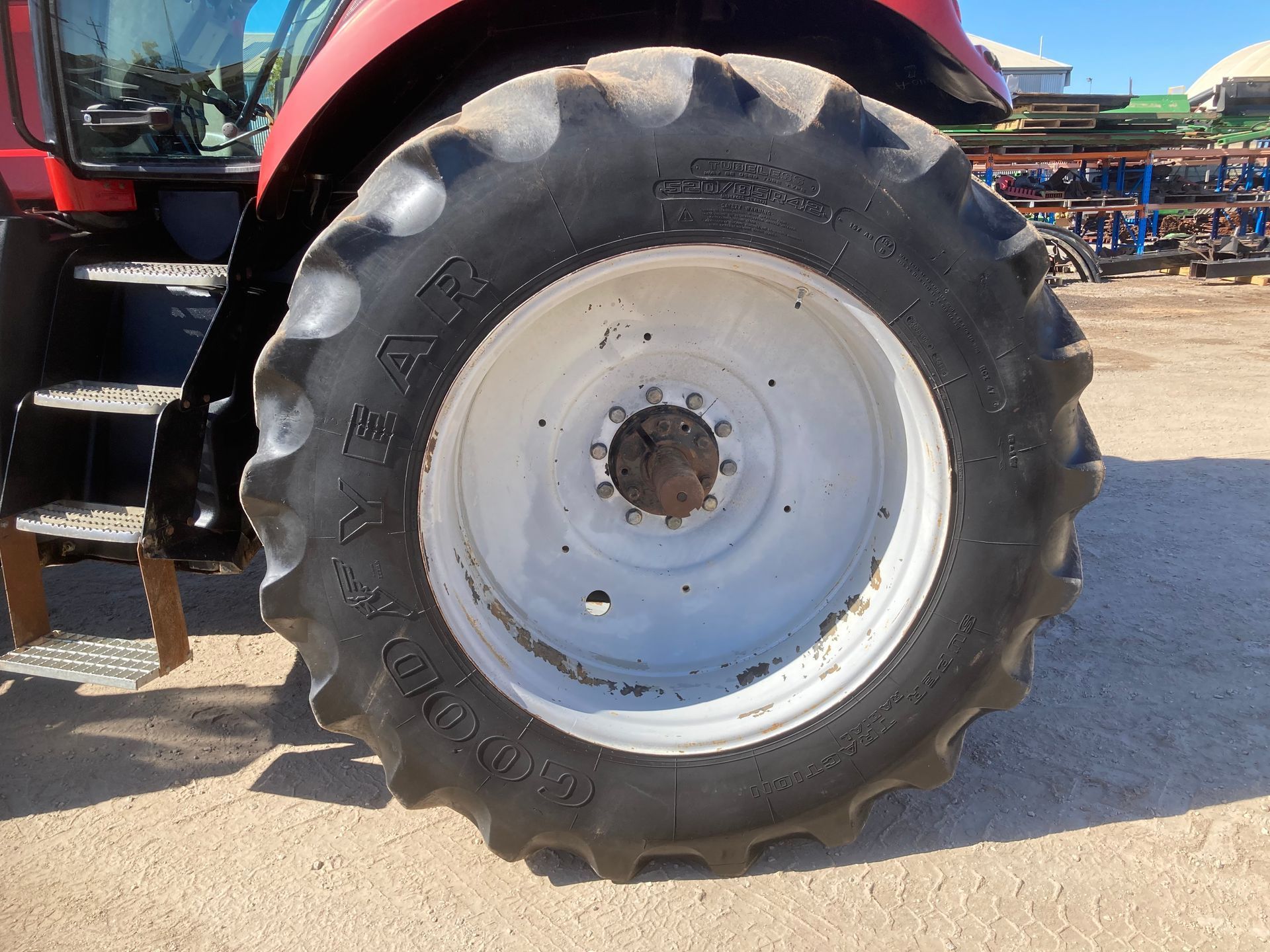Close-up of a large tractor tire with a white rim on a red farm vehicle