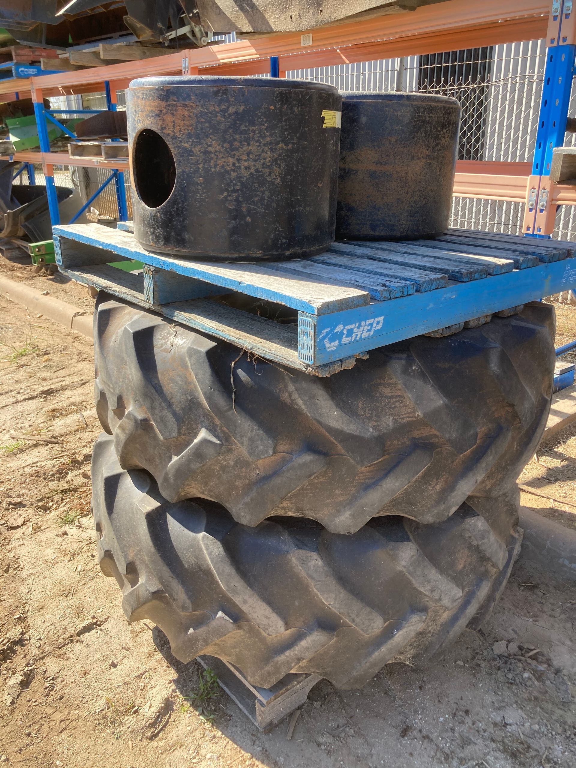 Blue metal platform on a large tractor tire, holding two black foam blocks outdoors