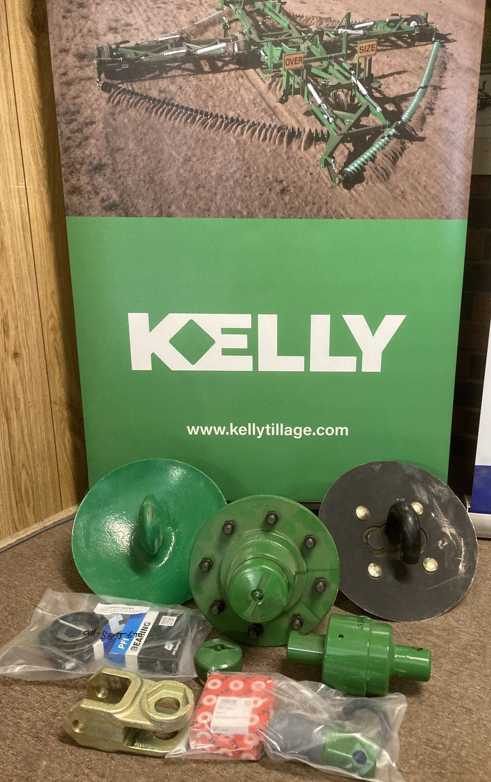 Kelly-branded product display with green metal parts and hardware on a table