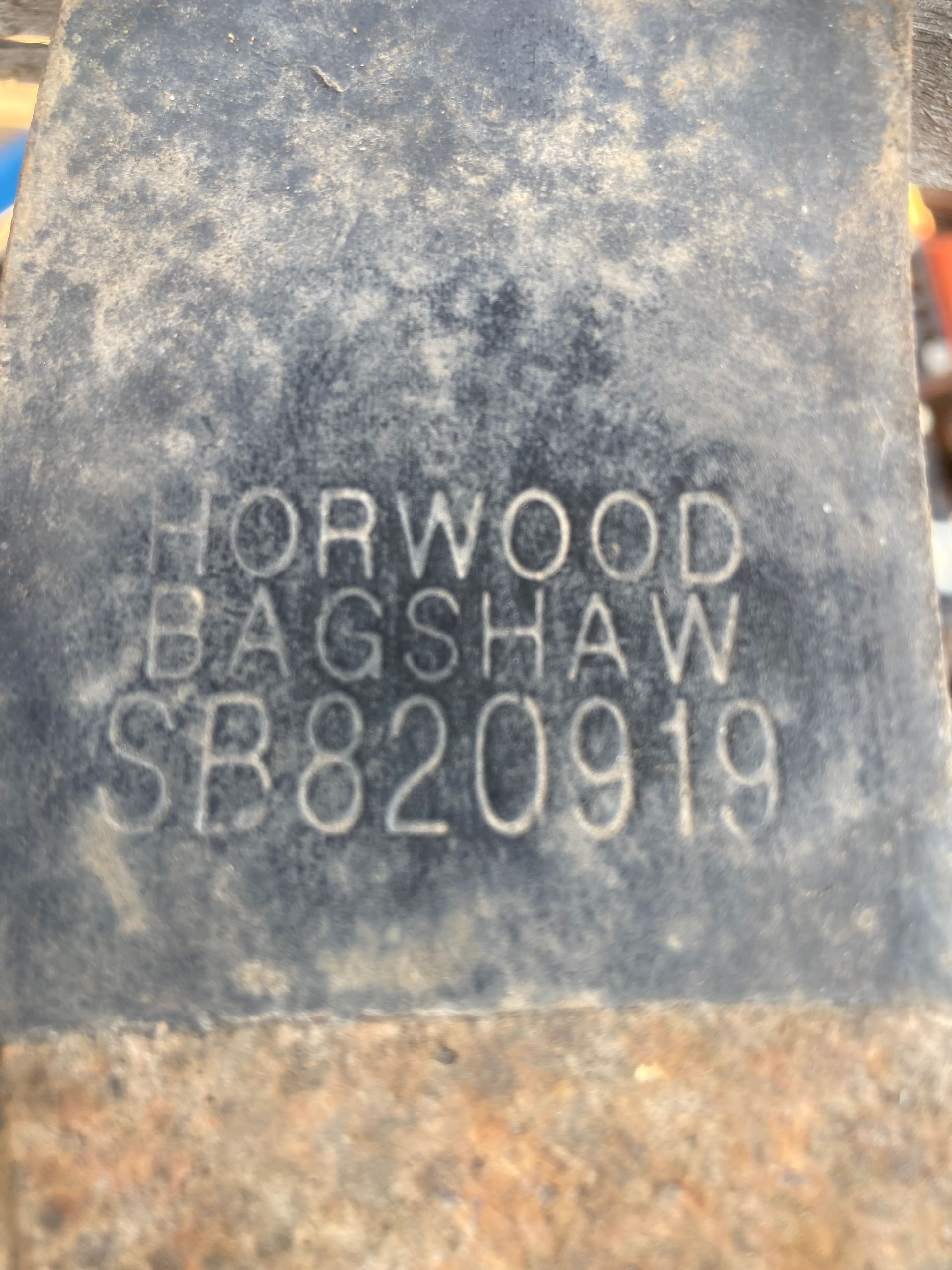 Close-up of a weathered metal plaque engraved “HORWOOD BAGSHAW SB820919.”