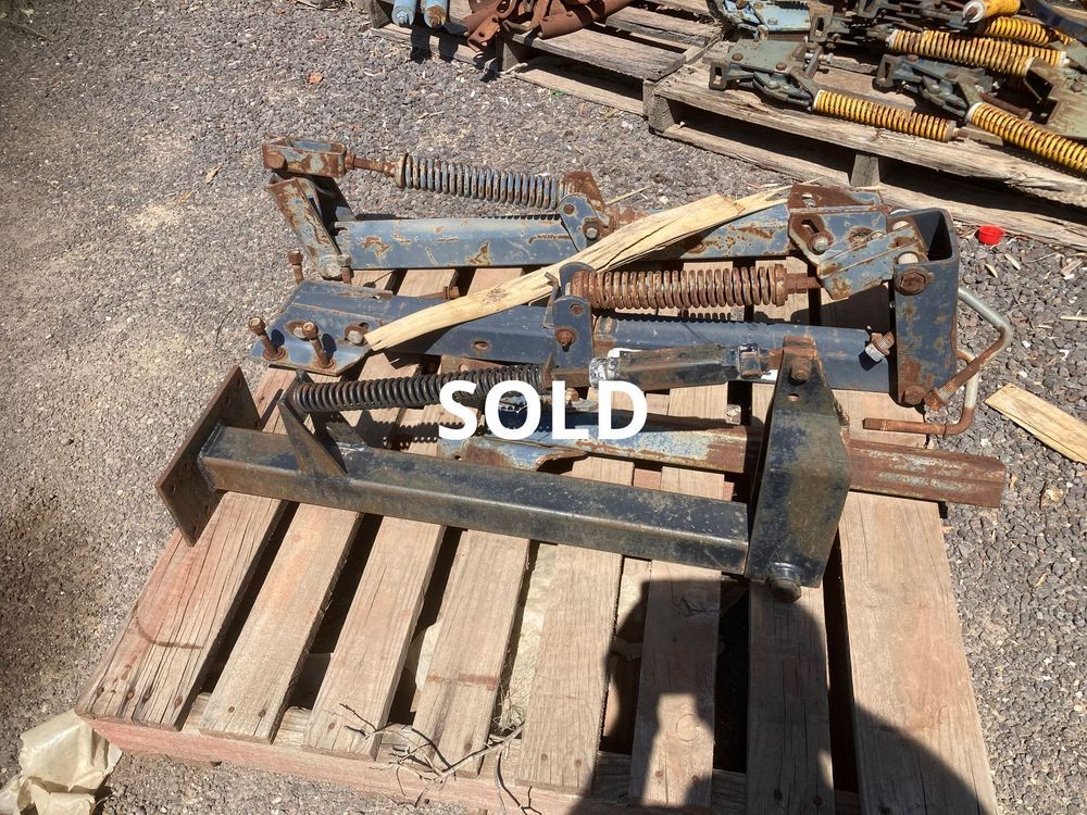 Rusty metal farm implement on a wooden pallet in a yard, marked SOLD.