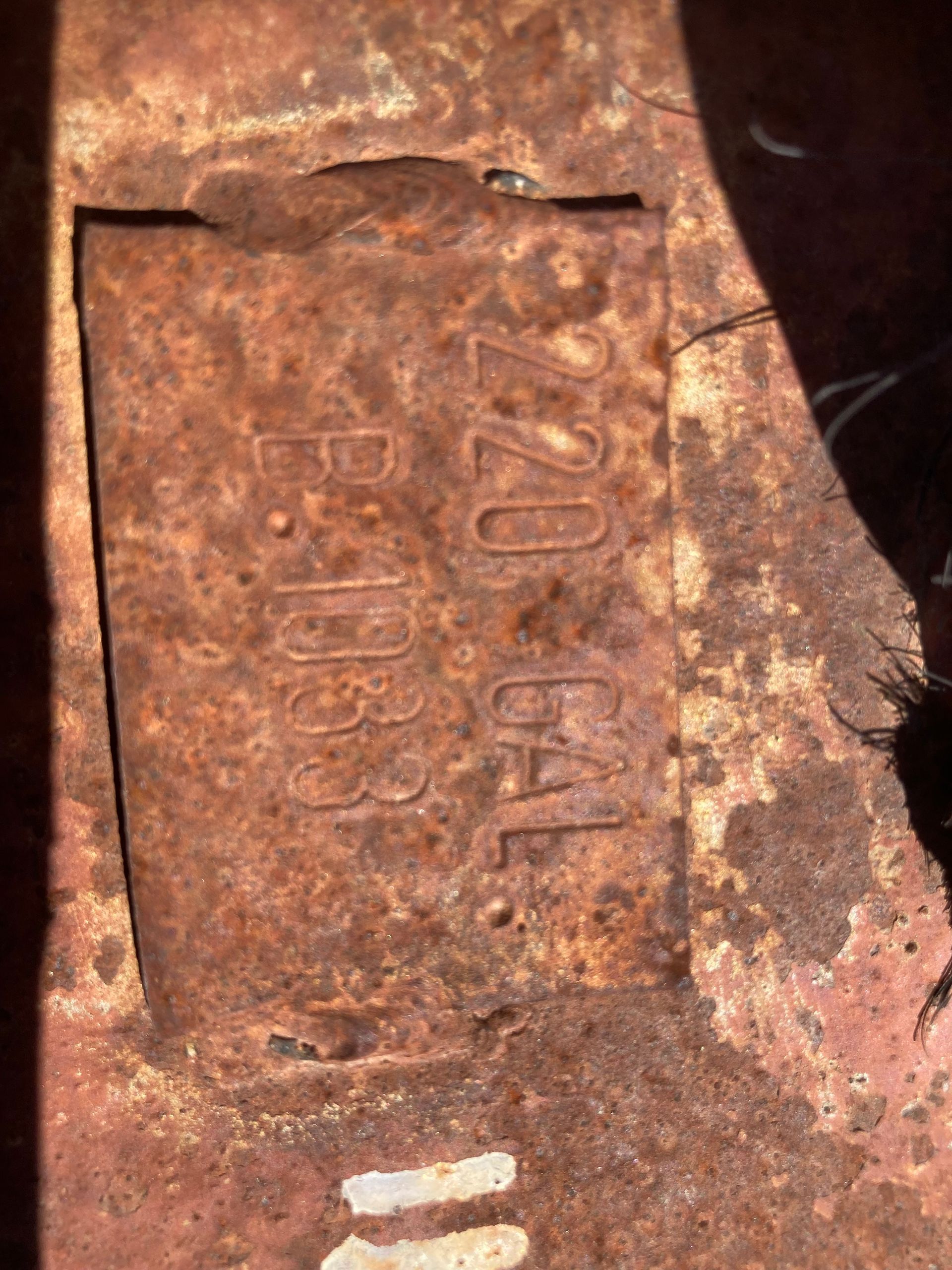Rusty metal plaque with faded embossed text on a rough surface