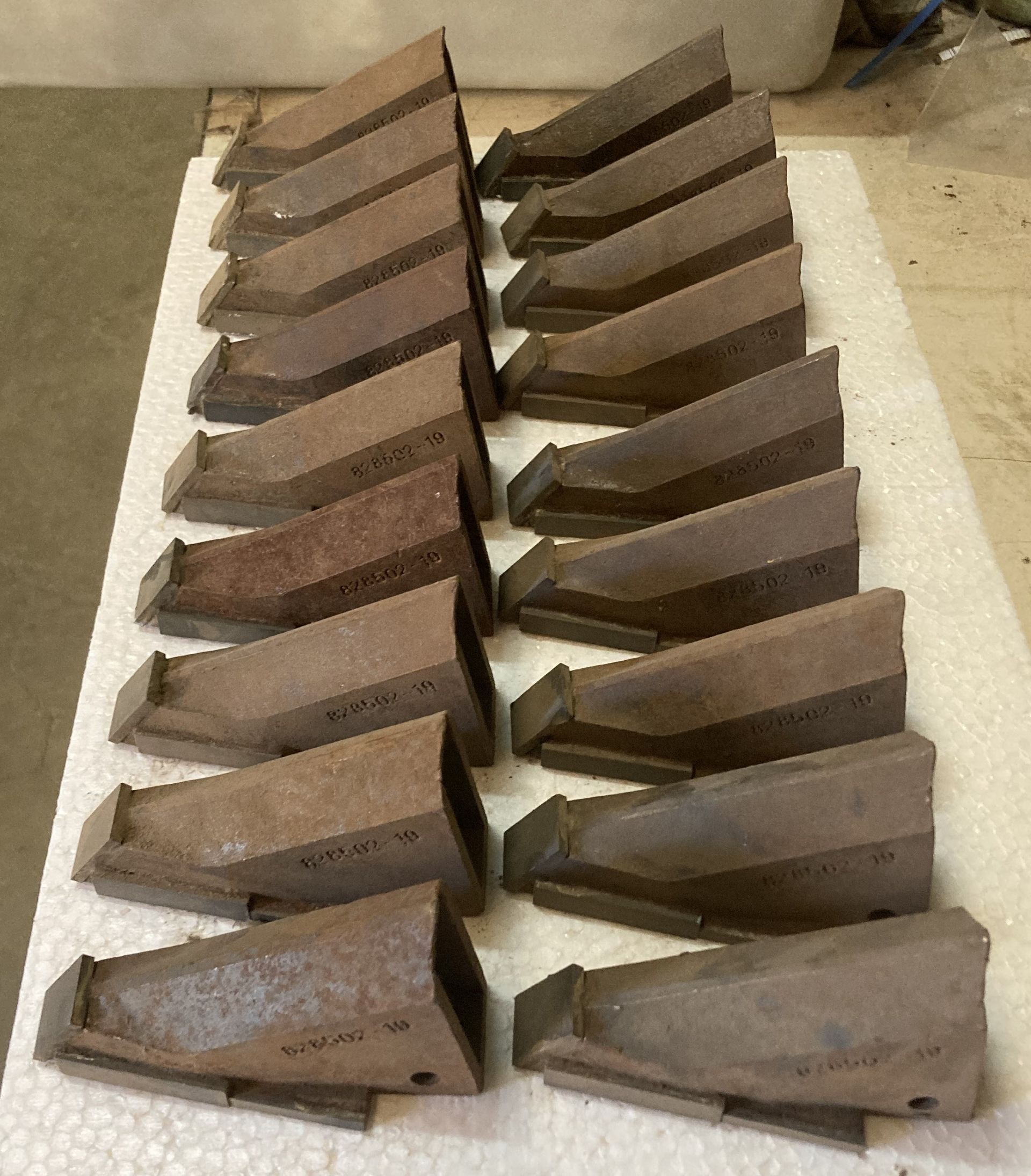 Two rows of rusted metal wedge blocks arranged on a white cloth background.