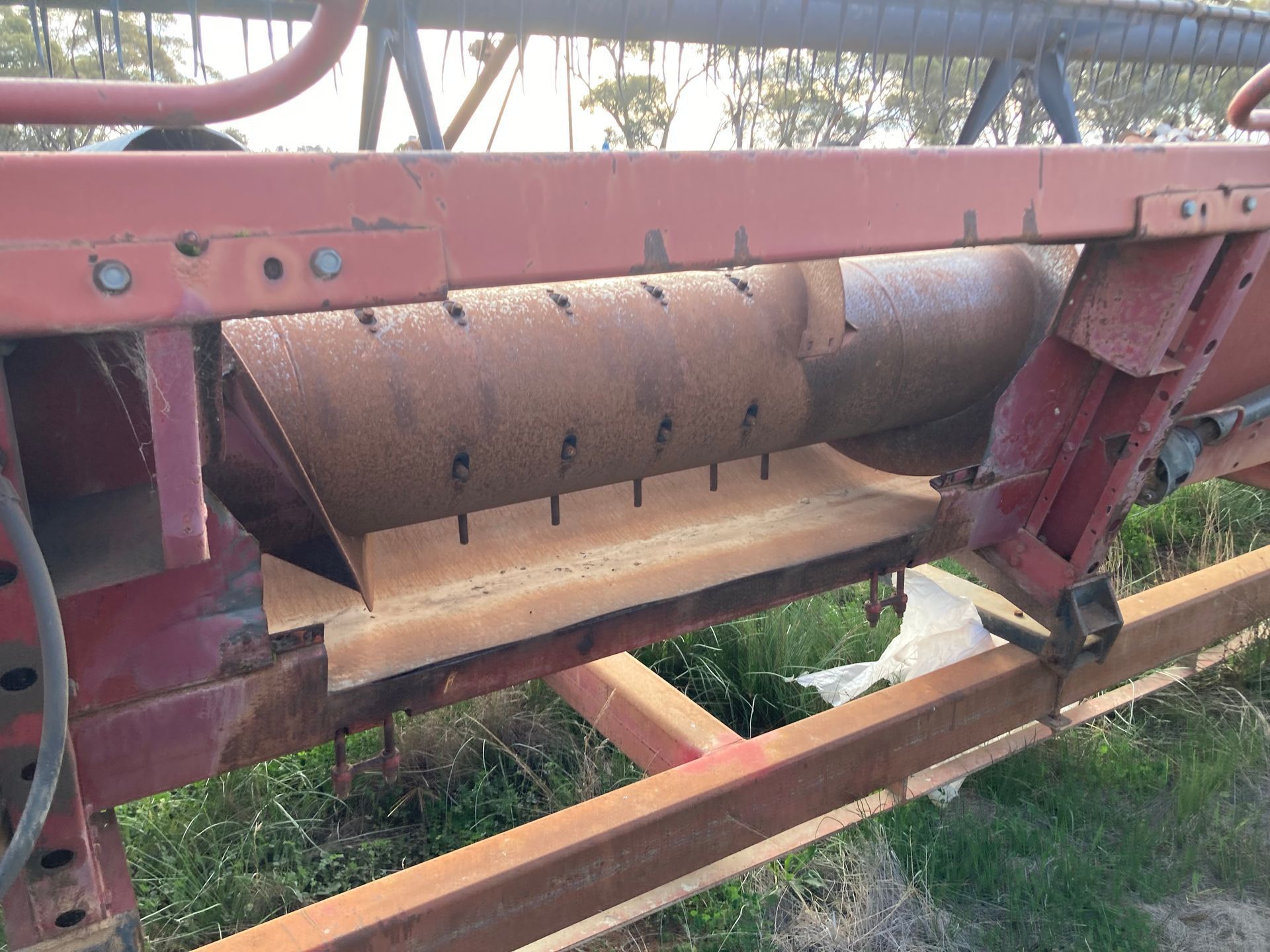 Rusty cylindrical machinery mounted on a red metal frame outdoors over grass