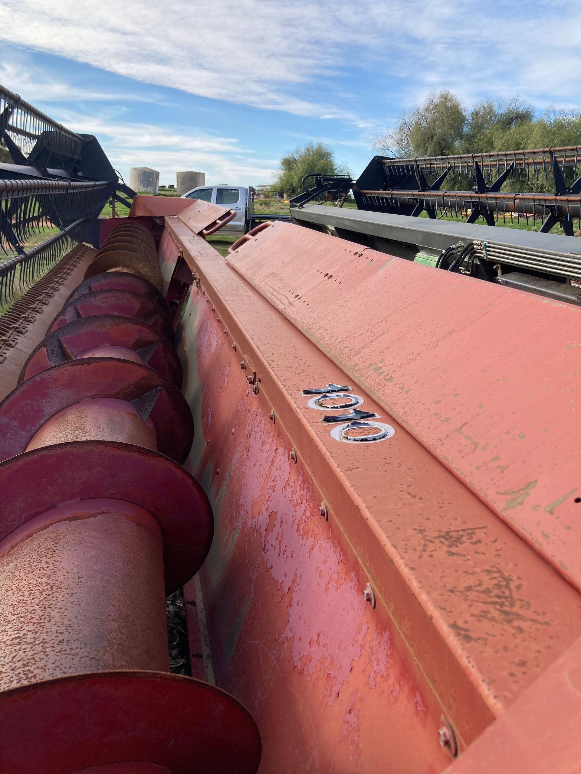 Close-up of a red industrial conveyor or hopper outdoors under a blue sky.