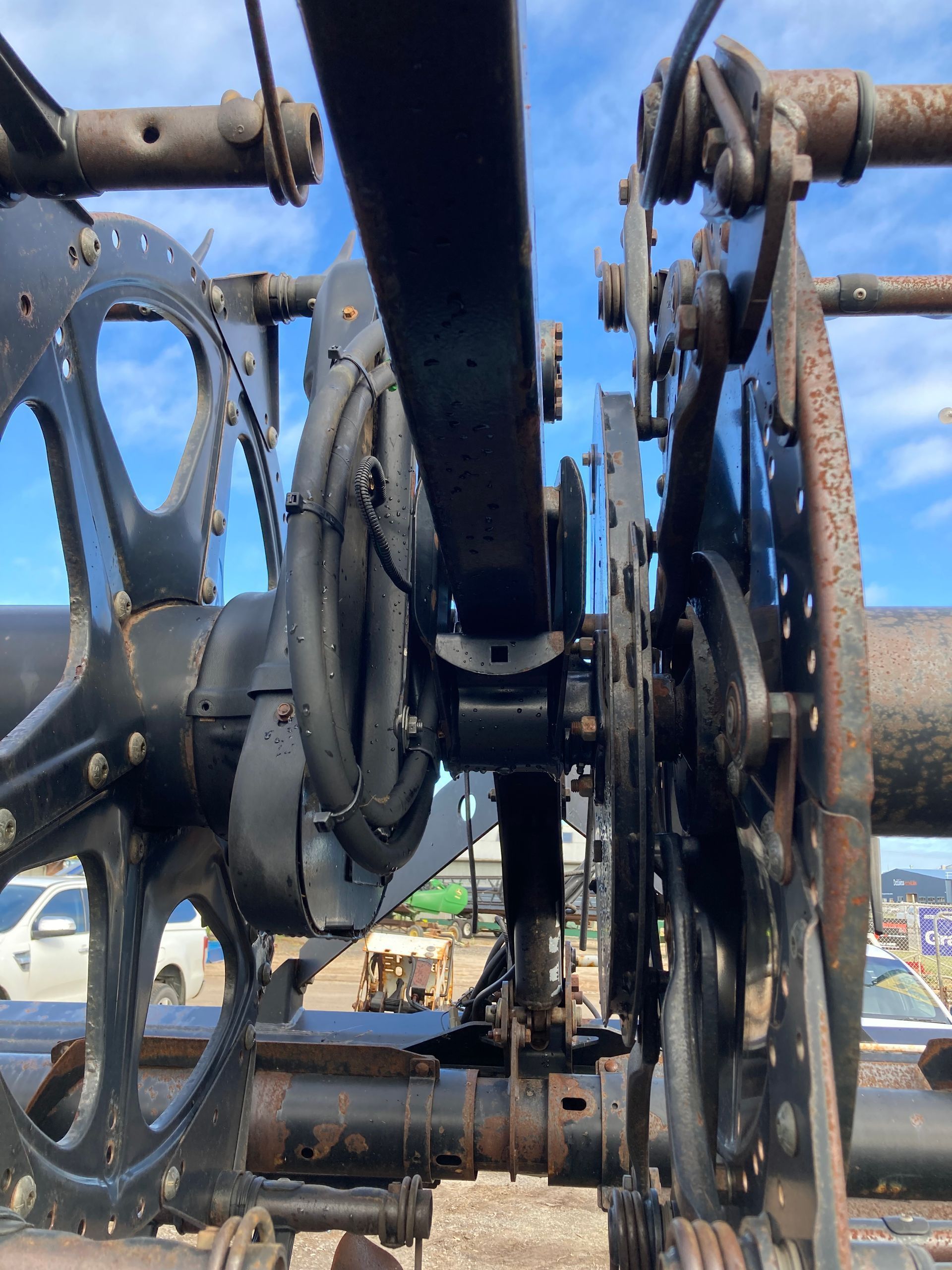Close-up of a blue and black industrial machine wheel and gears against a bright sky
