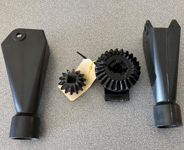 Black and tan plastic gear parts and two tapered nozzle-like pieces on a white background