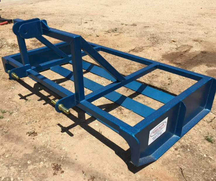 Blue metal trailer frame on dirt ground, viewed from above