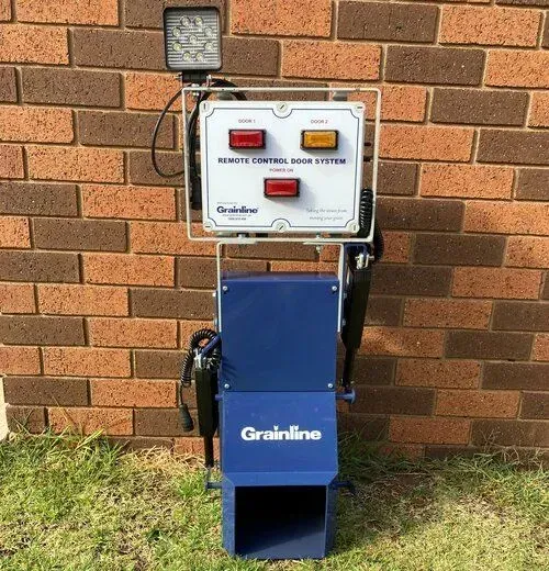 Blue Grainline remote control box mounted on a brick wall with warning lights and buttons