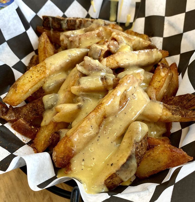 A basket of french fries with cheese sauce on a checkered paper
