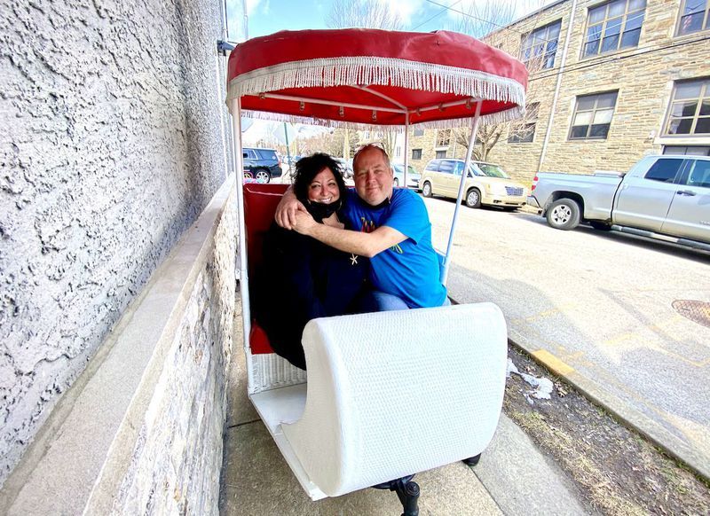 A man and a woman are sitting in a rickshaw.