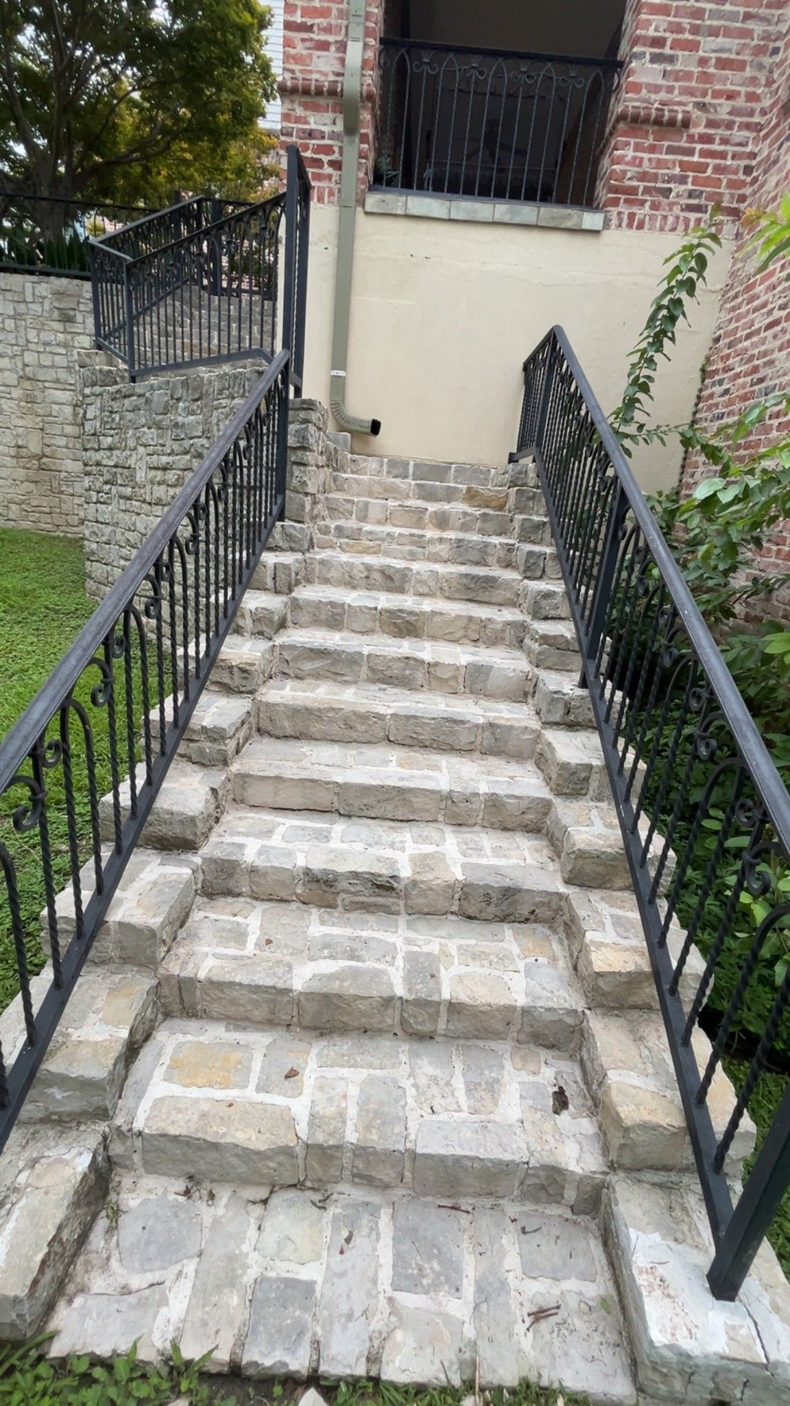 Steep stone stairway with black railings leading up to a brick building entrance