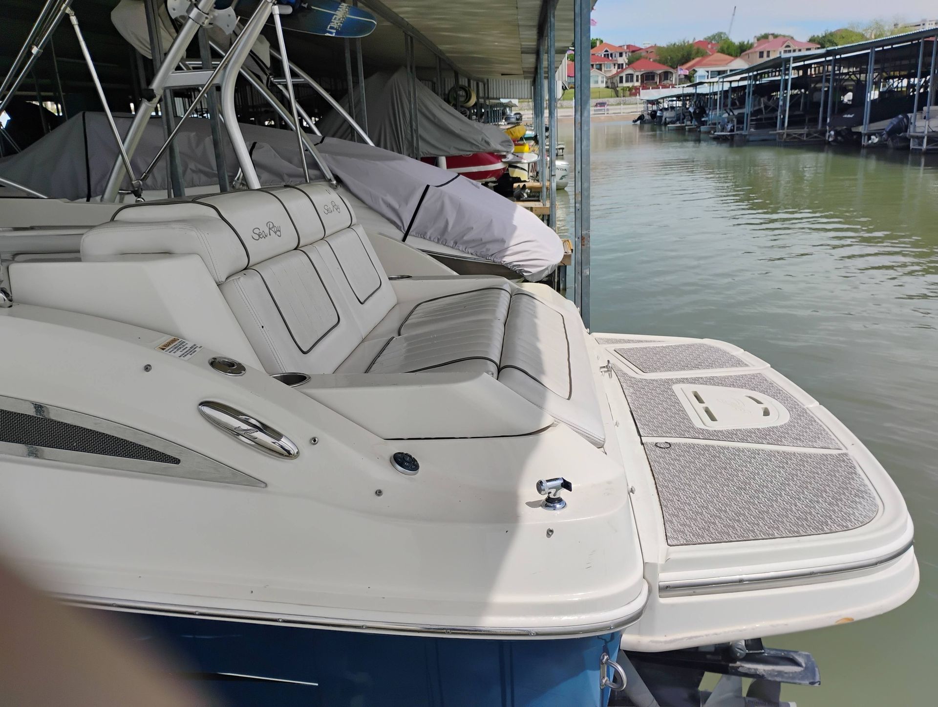 White motor yacht docked at a marina with cushioned seating and calm water alongside