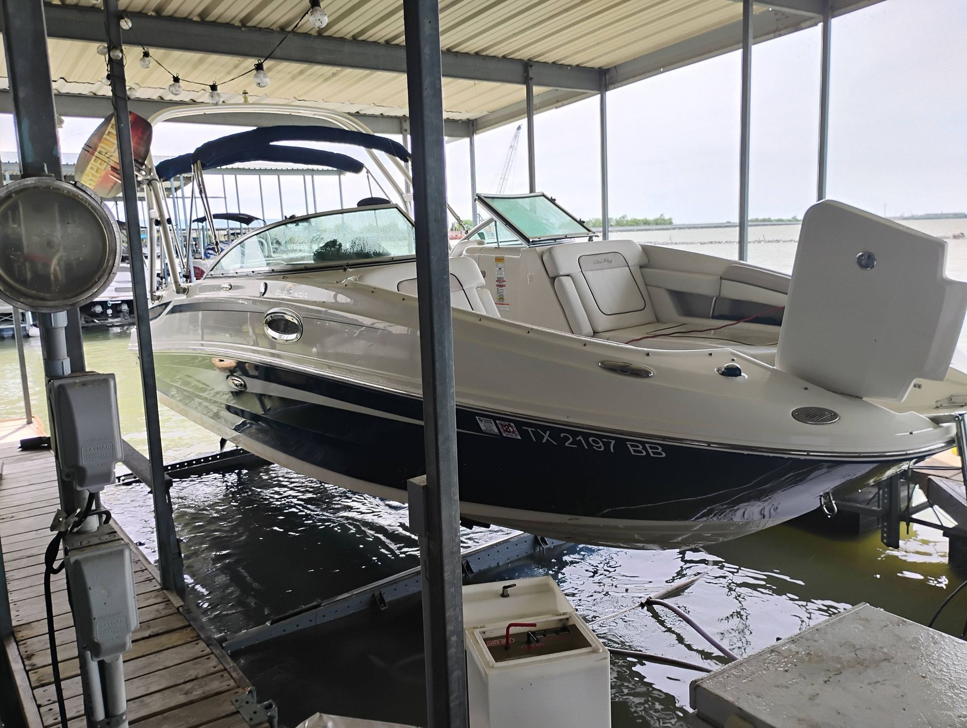 White and black motorboat docked under a covered marina slip on calm water