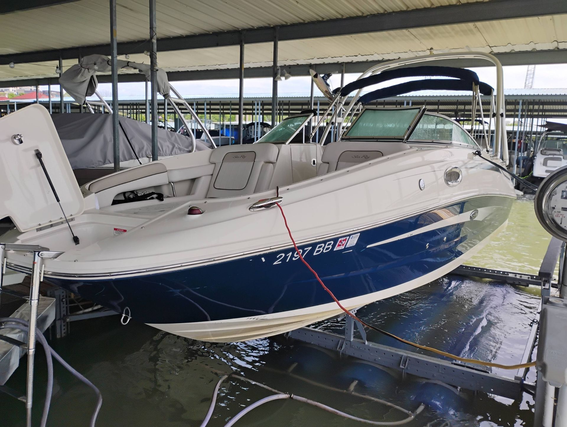 Blue-and-white motorboat docked under a covered marina, with seats and canopy visible