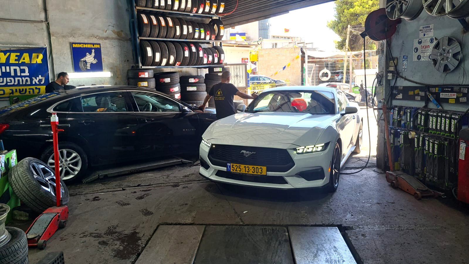 כב ספורט פורד מוסטנג לבן במהלך בדיקת גלגלים או תיקון פנצ'ר בירושלים.