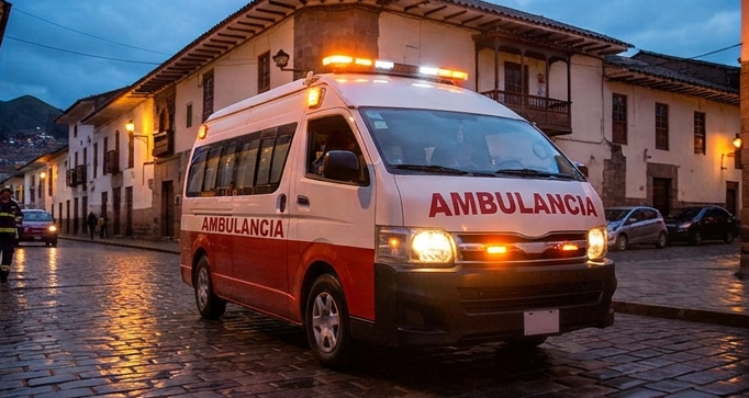 Tres paramédicos están junto a una ambulancia blanca con franjas rojas y luces azules intermitentes.