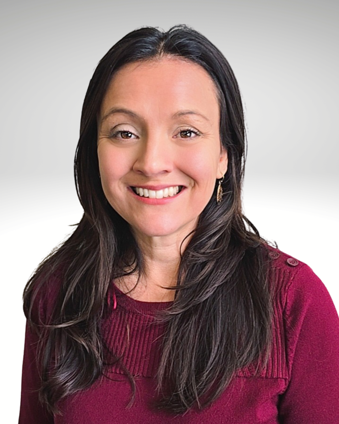 Smiling woman with long dark hair wearing a burgundy sweater against a light gray background