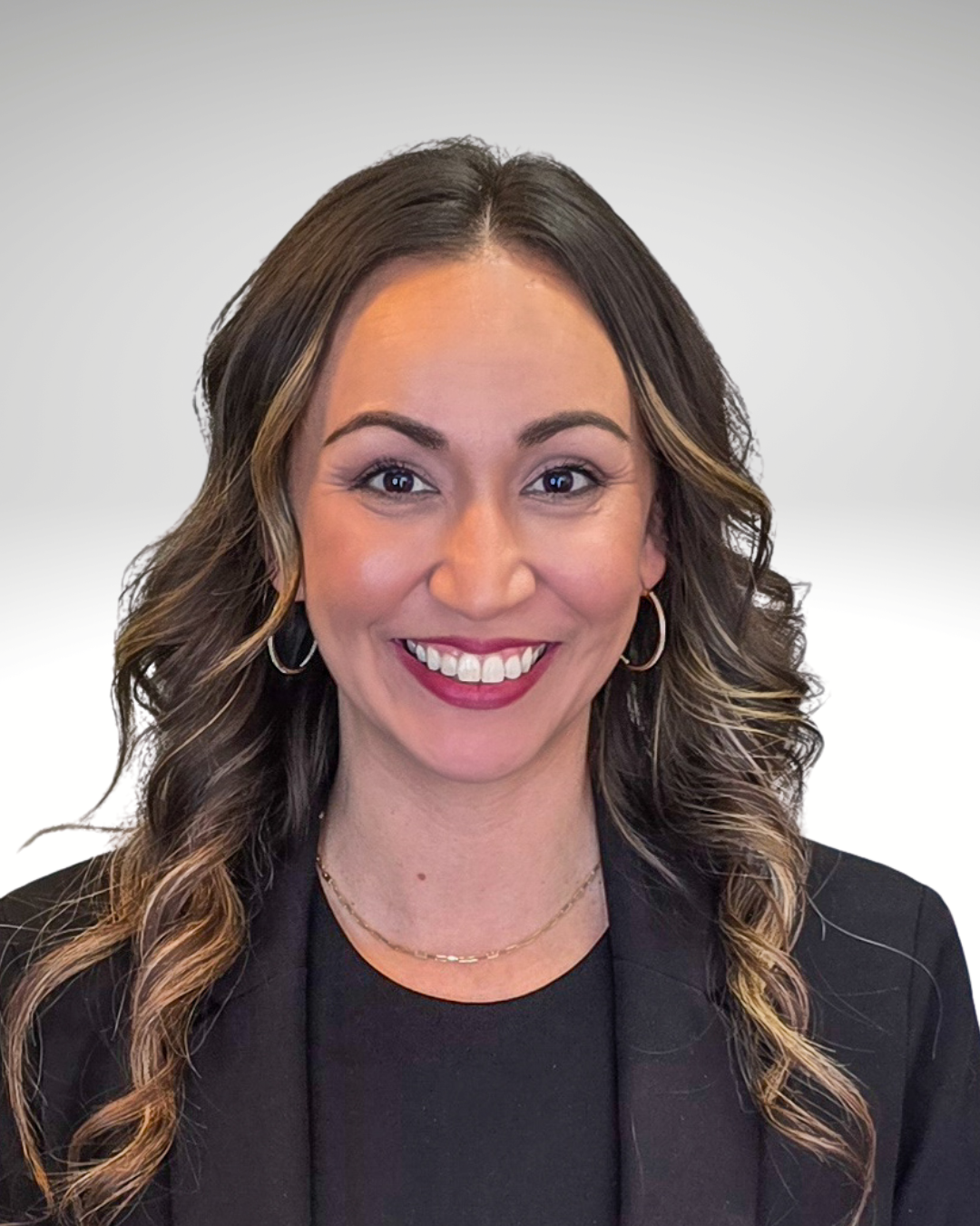 Portrait of a smiling woman in a black blazer against a light background