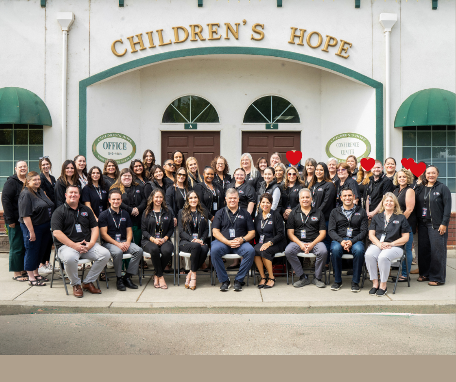 Large group posing outside Children’s Hope building, with green awnings and storefront-style entrance.