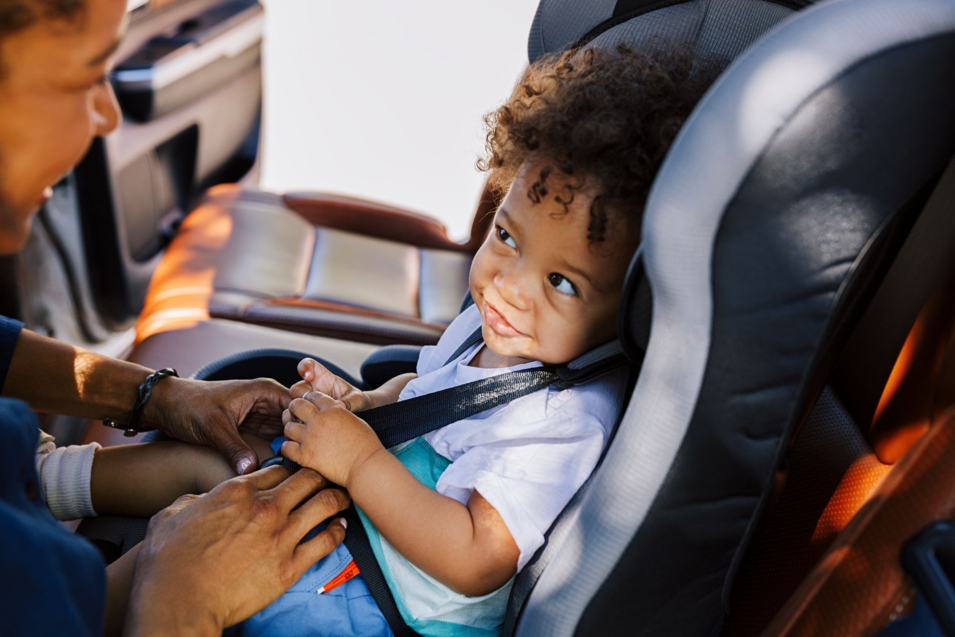 A woman is putting a baby in a car seat.