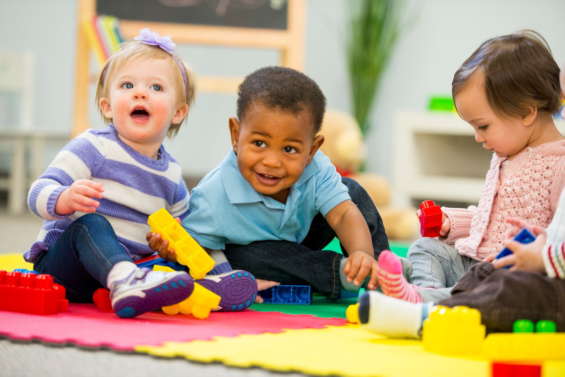 A group of babies are sitting on the floor playing with blocks.