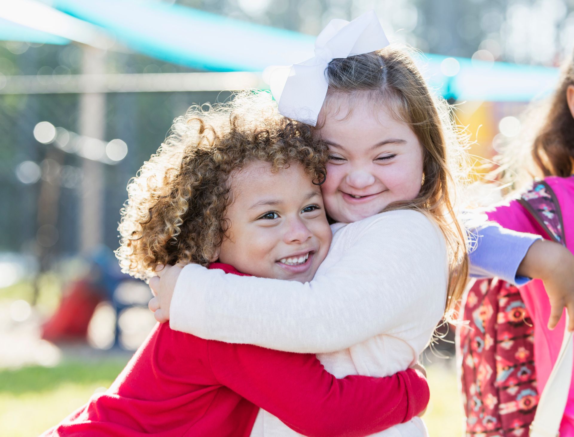 A boy and a girl are hugging each other in a park.