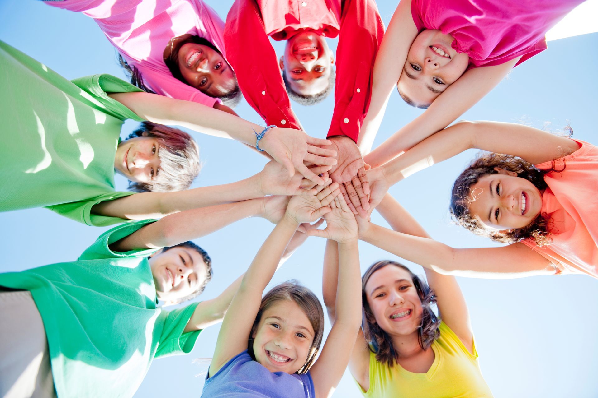 A group of children are putting their hands together in a circle