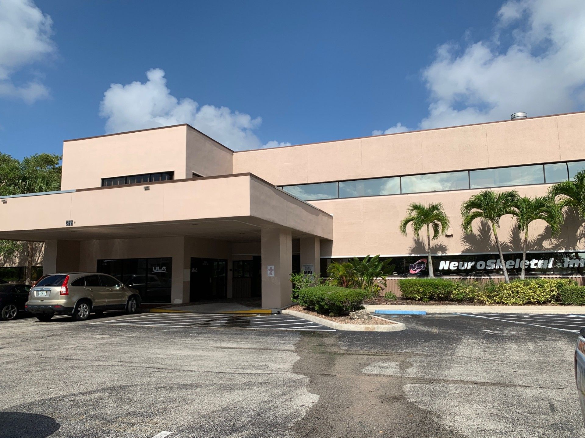 A large building with cars parked in front of it on a sunny day.