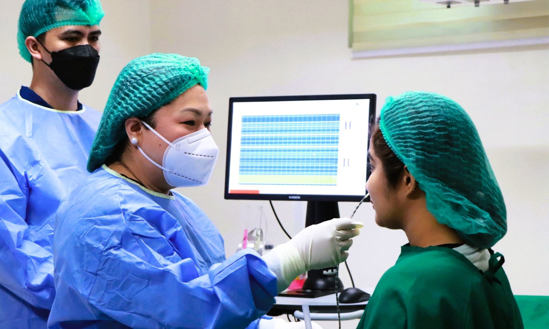 Medical professionals performing a nasal swab on a patient in a sterile examination room.