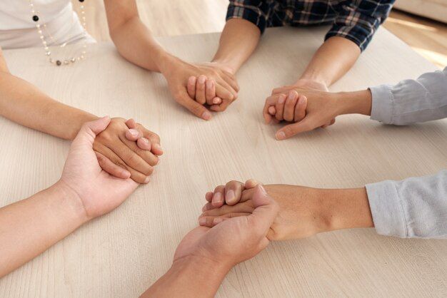 Five people holding hands in a circle around a light-colored table.