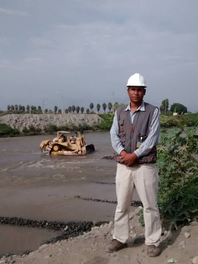 Obreros viales manejan una apisonadora amarilla para pavimentar una calle junto a conos de tráfico naranjas.