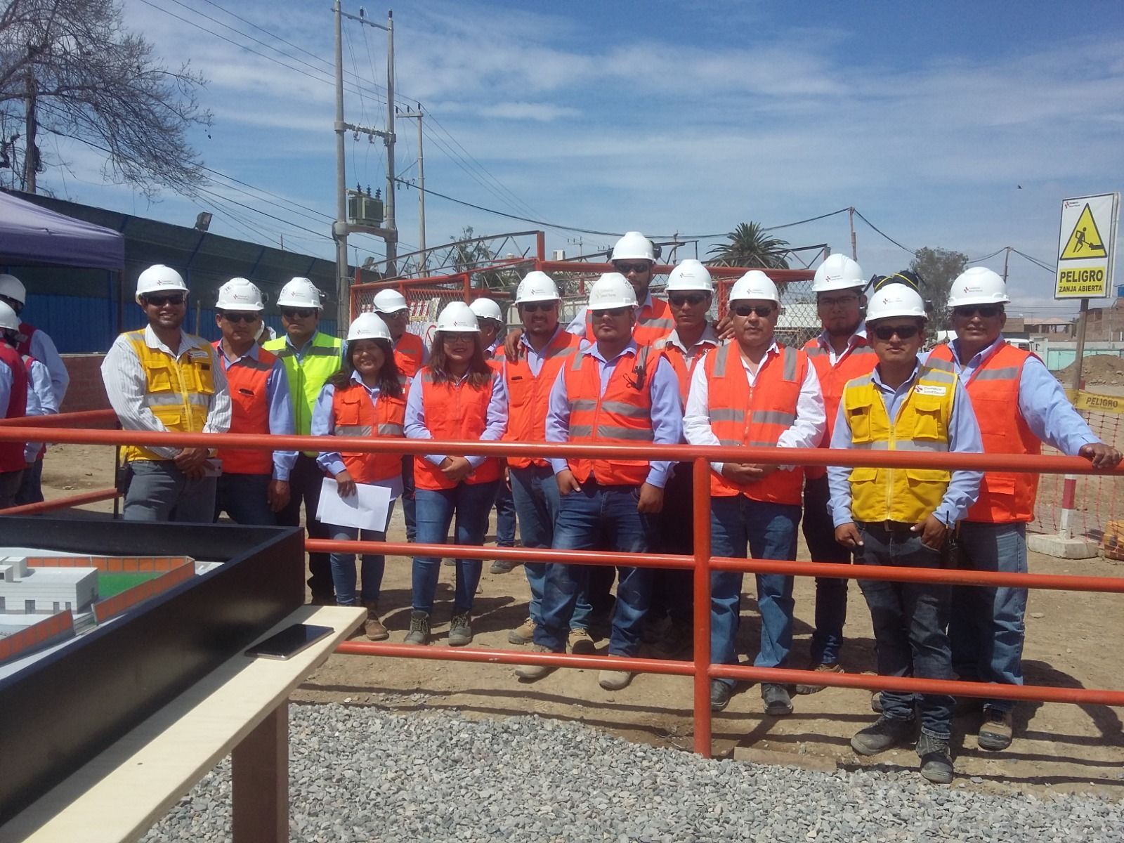 Trabajadores con cascos y chalecos de seguridad de pie juntos en un andén ferroviario cerca de las vías y el equipo.