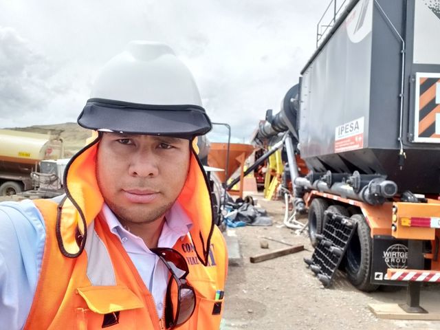 Equipo de construcción de carreteras con excavadoras en una carretera de montaña, bloqueando el tráfico con conos y barriles.