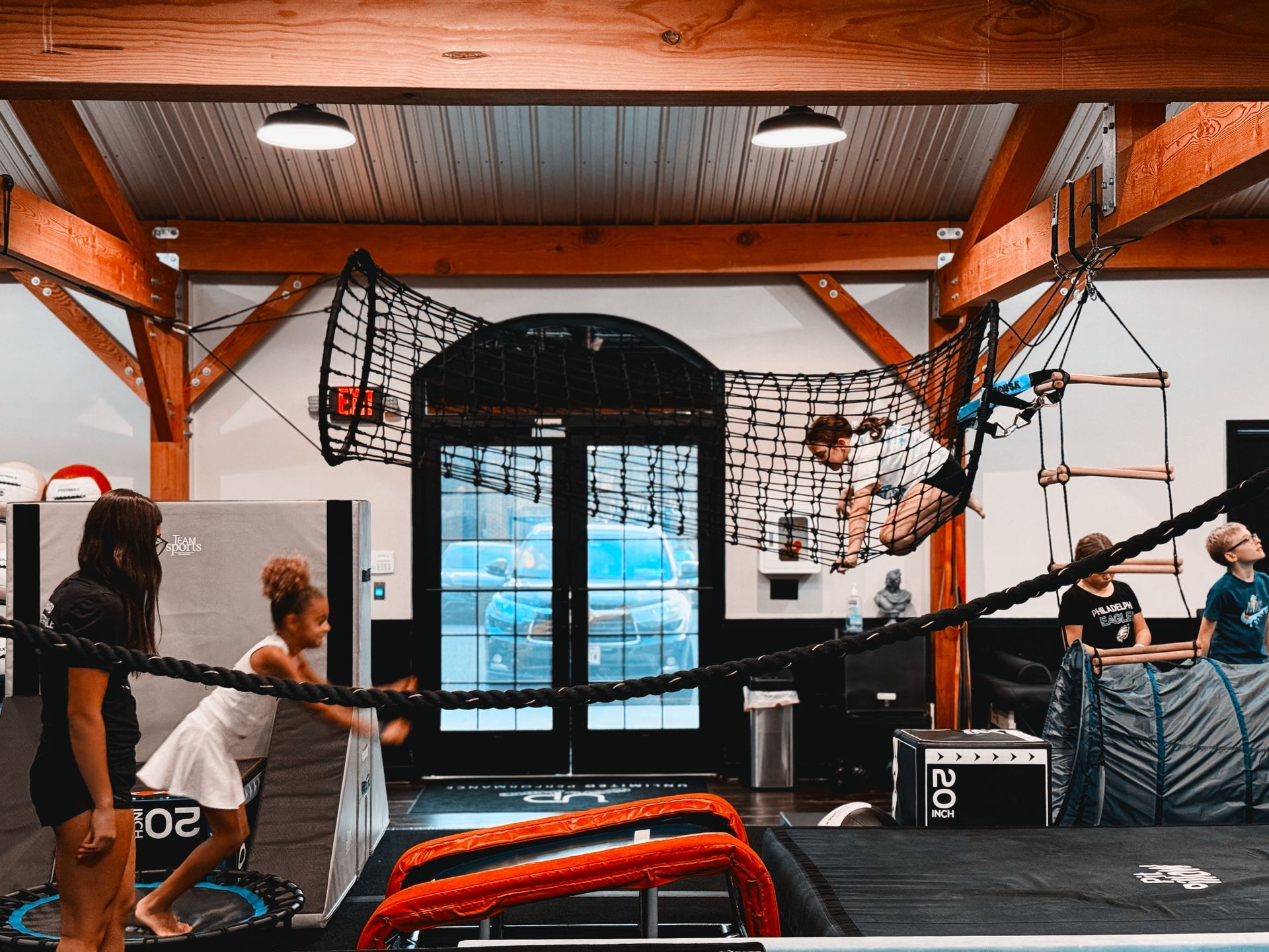 People exercising in a gym in Gibbsboro, NJ, using cables and ropes around a boxing ring and padded equipment.