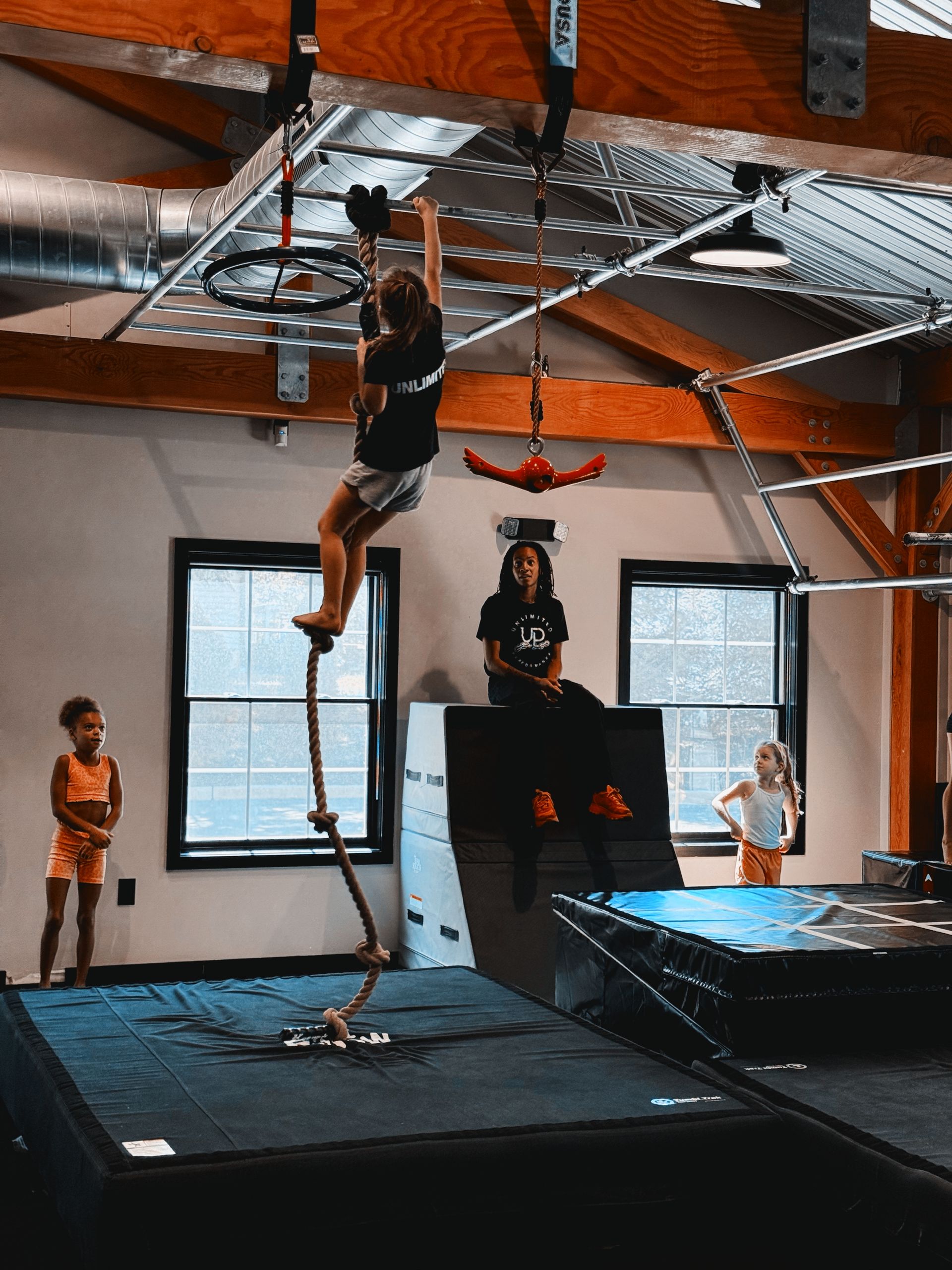 Children in a gym in Gibbsboro, NJ use ropes and trampolines in an indoor obstacle course