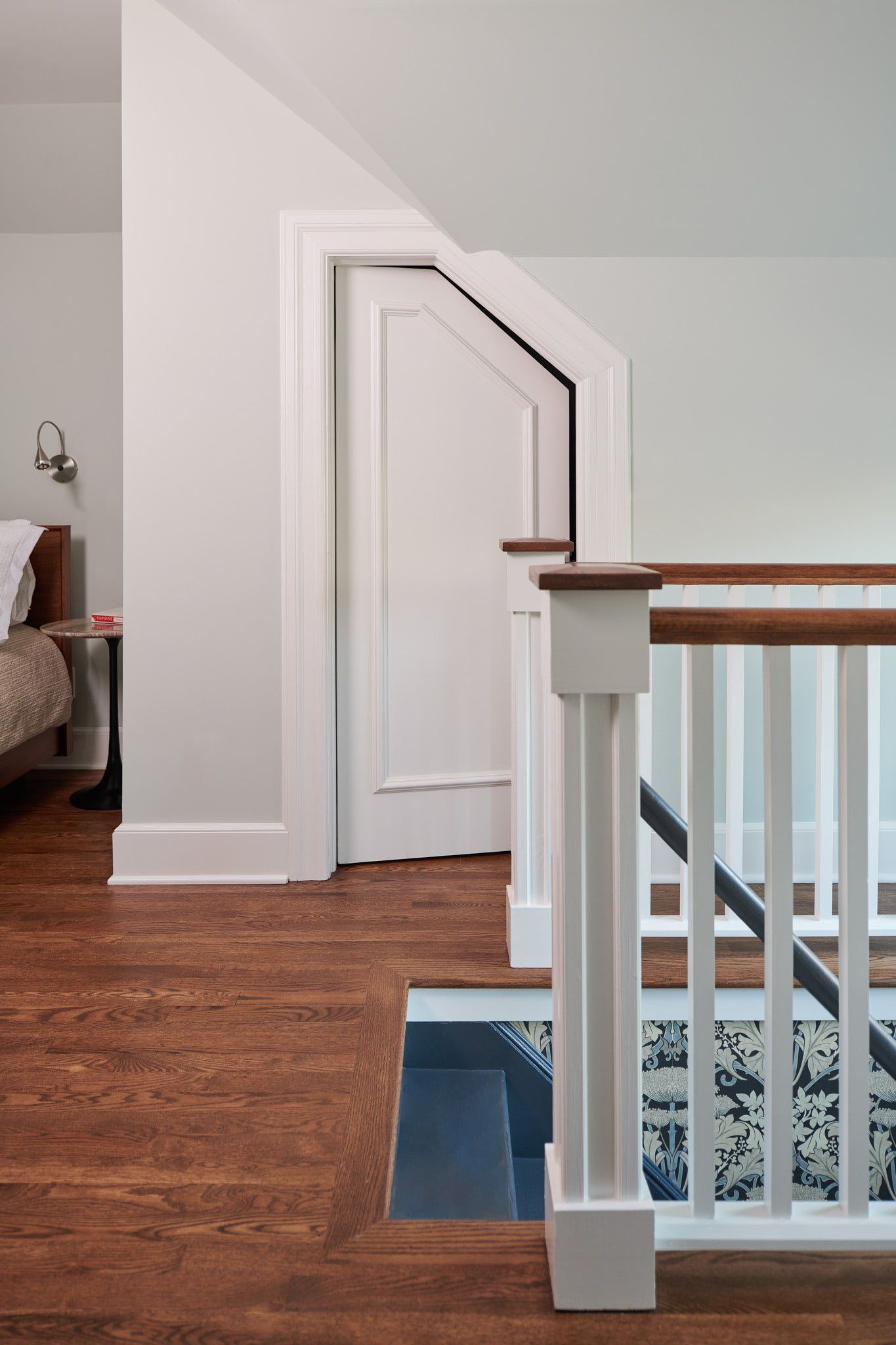 A staircase with a wooden railing leading up to a bedroom.