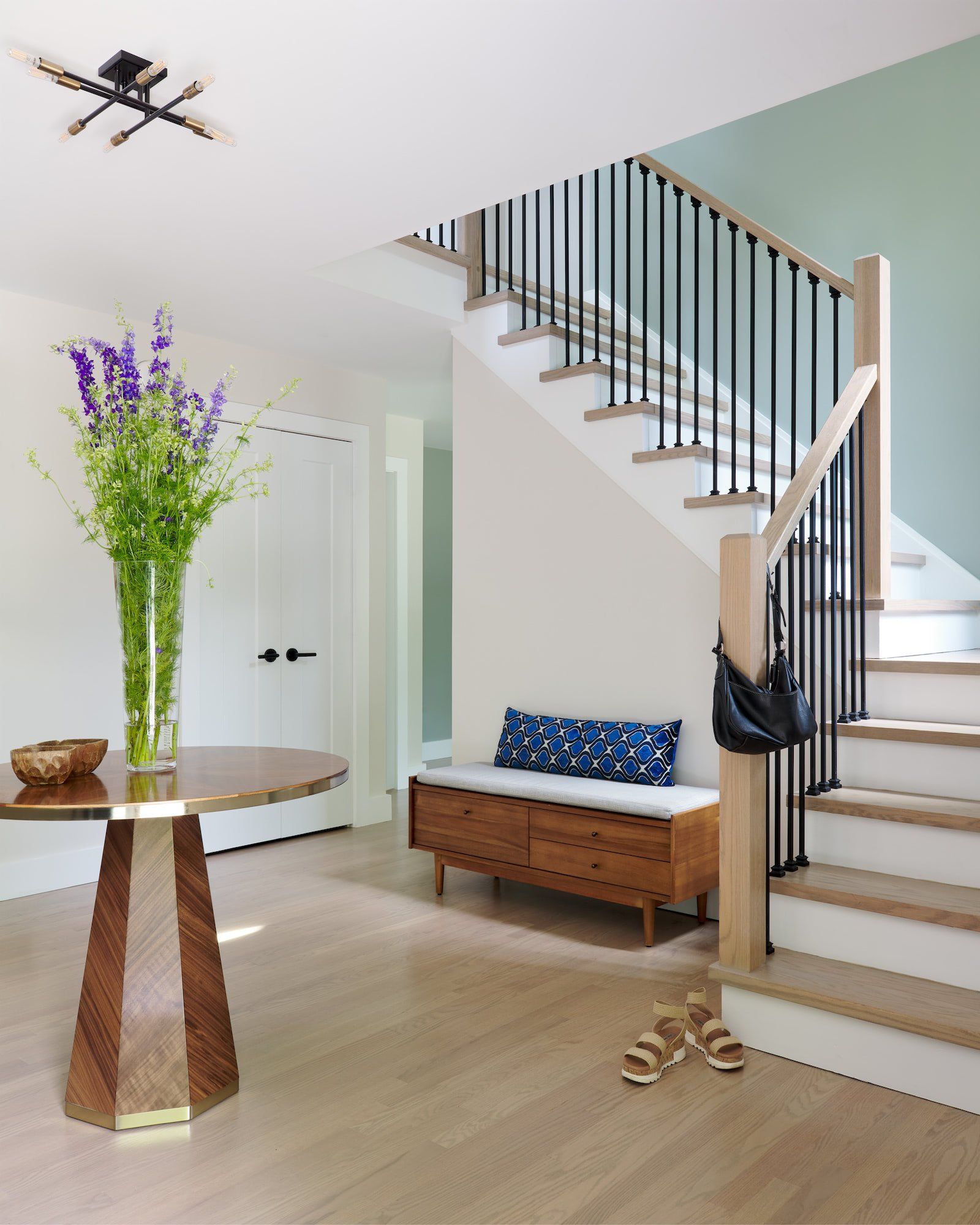 A hallway with stairs and a table with flowers on it